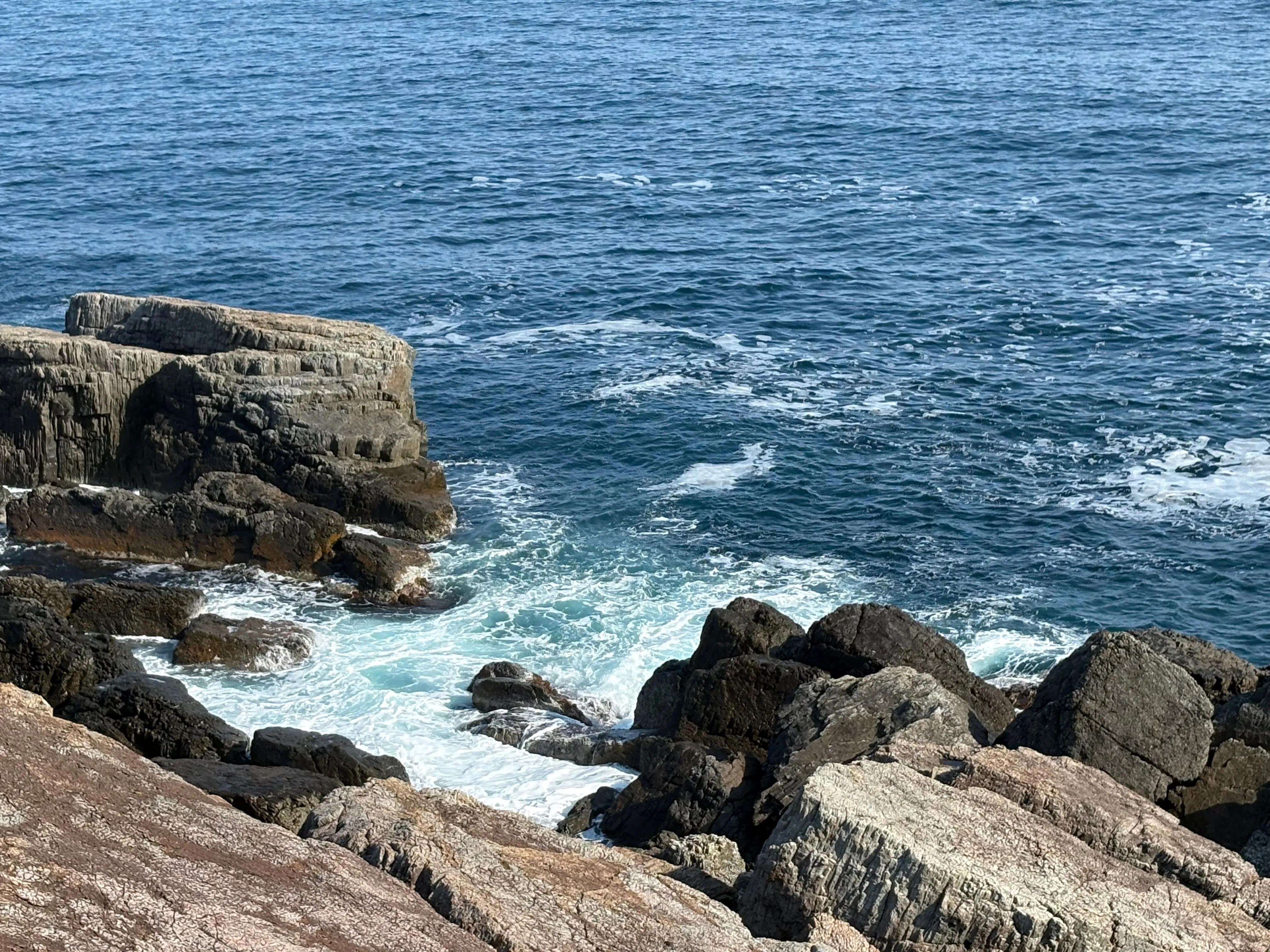 ごつごつとした岩が広がる海岸。波が打ち寄せる。