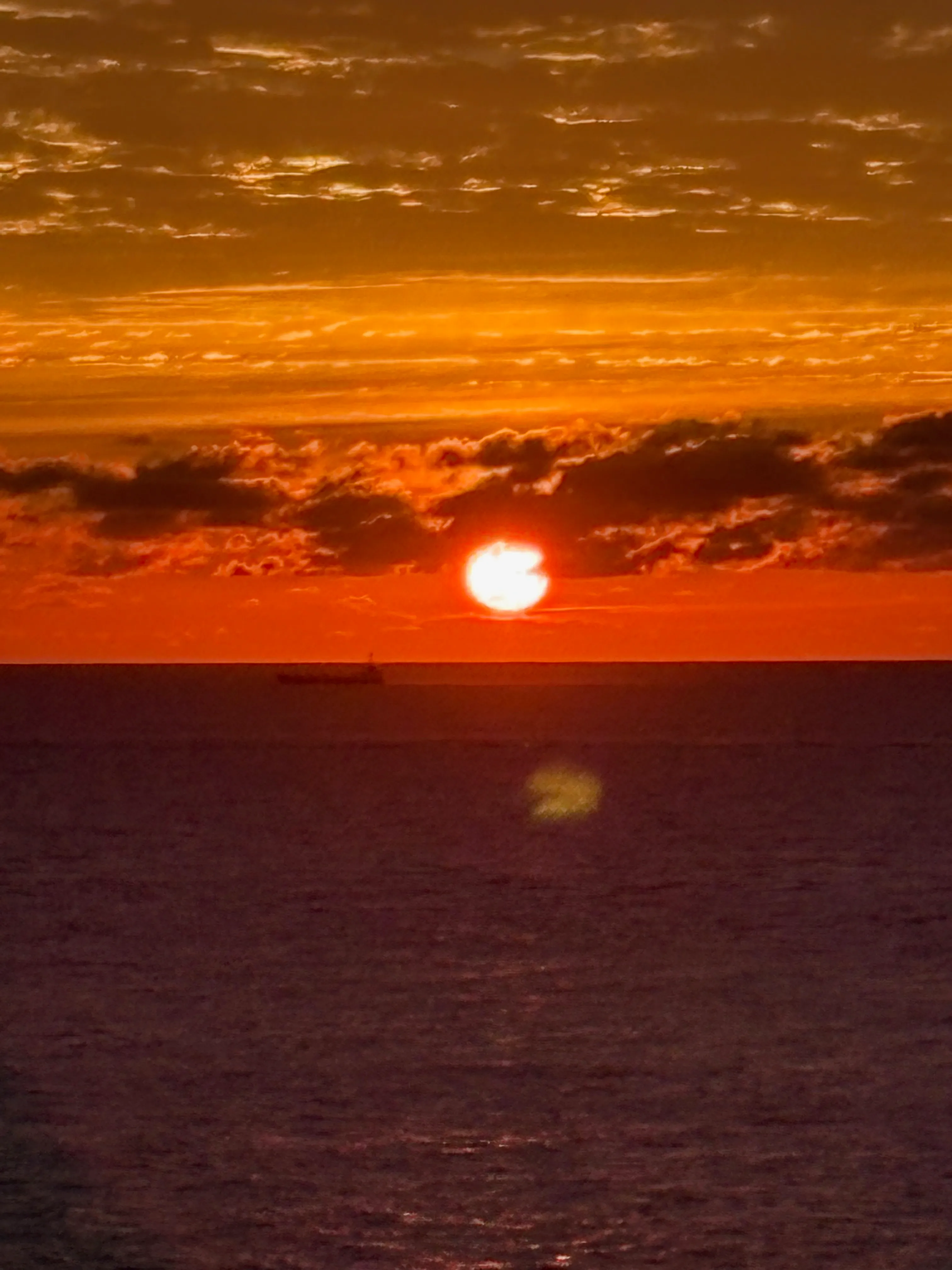 水平線に沈んでいく夕日。空と海がオレンジに染まる。