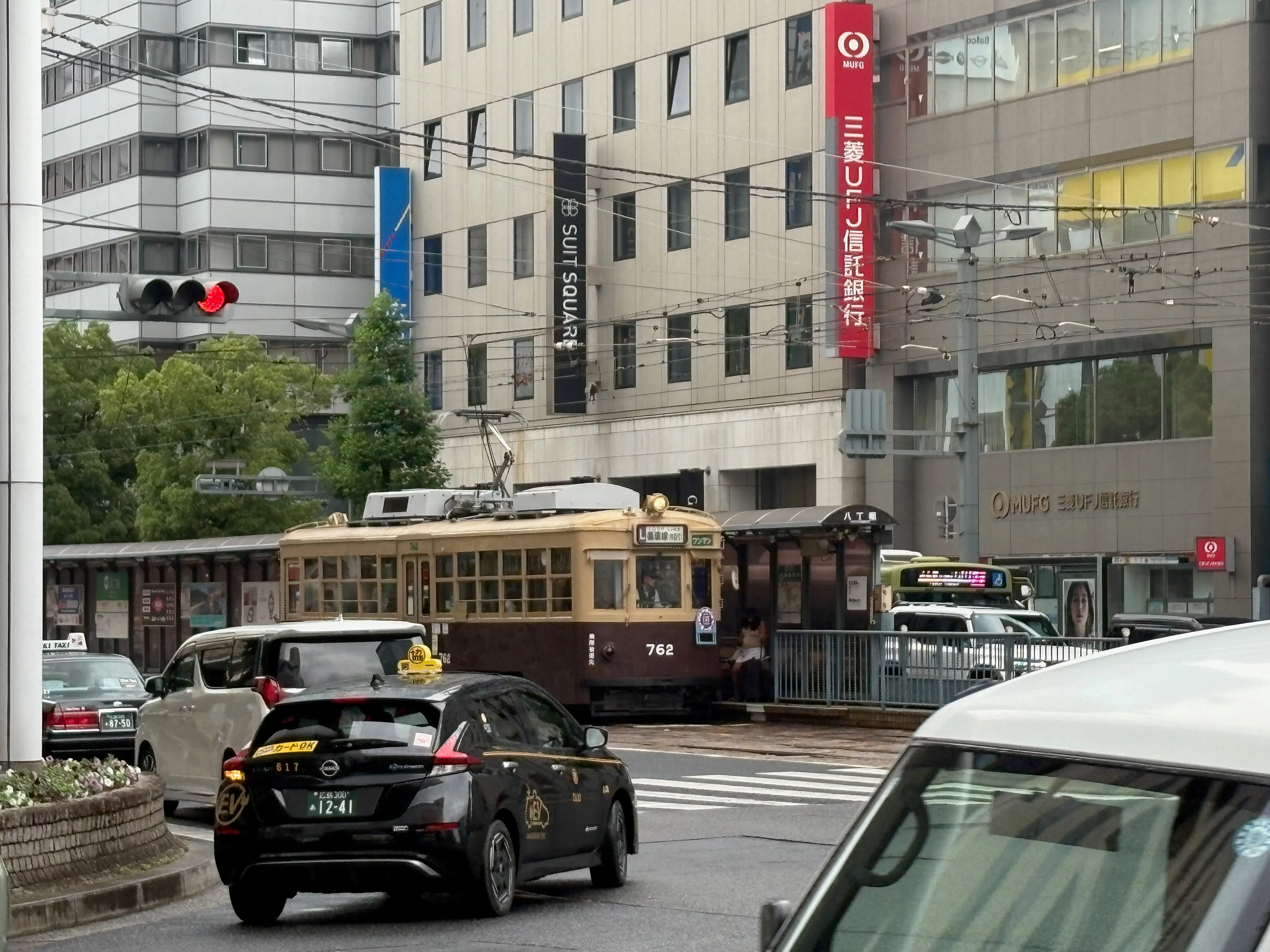 広島電鉄の路面電車。街なかの交差点を走る茶色い車両。